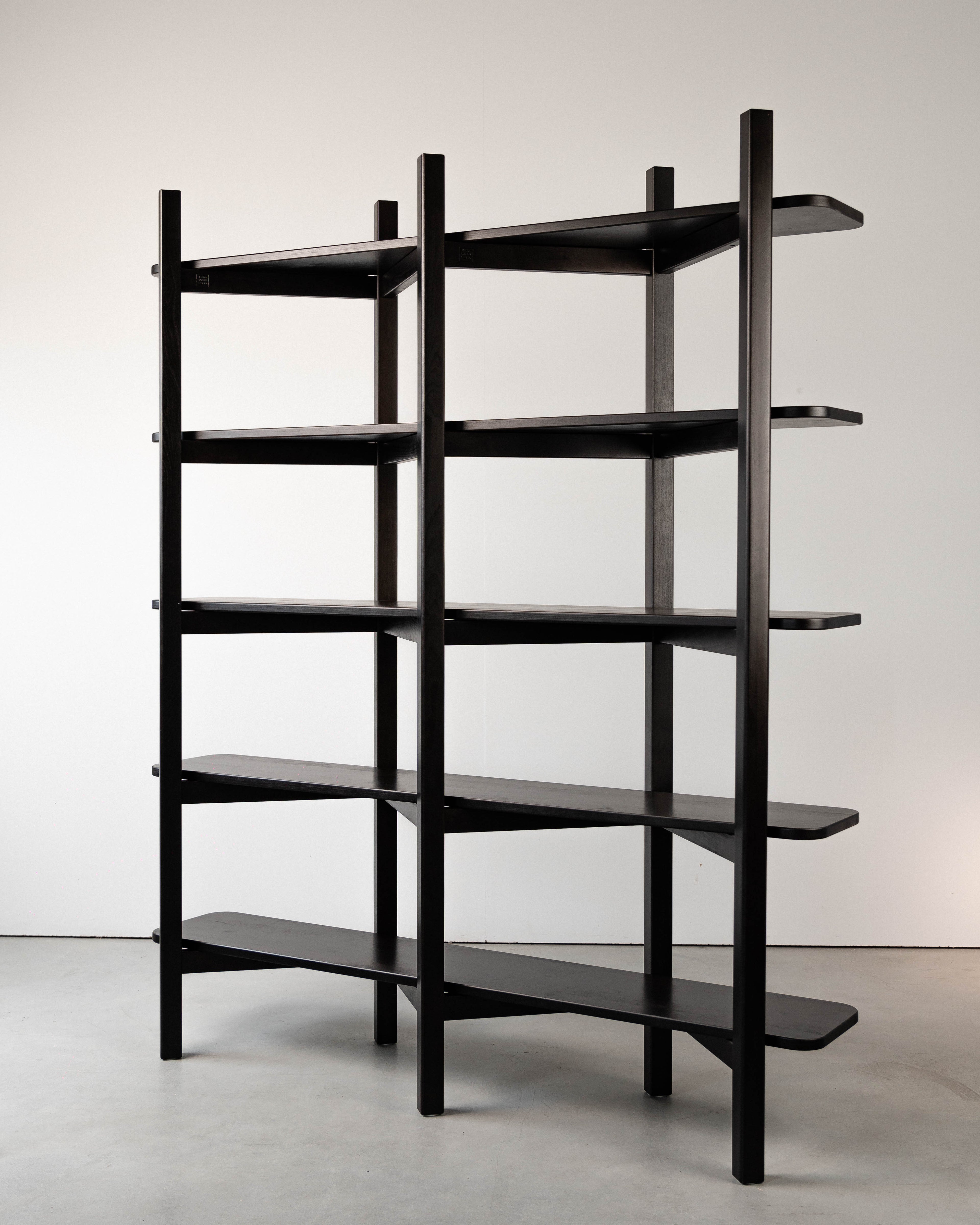 Ciemny dębowy regał modułowy w stylu mid-century modern, czarno-brązowy, z czterema pionowymi słupkami i pięcioma półkami. Minimalistyczny design.